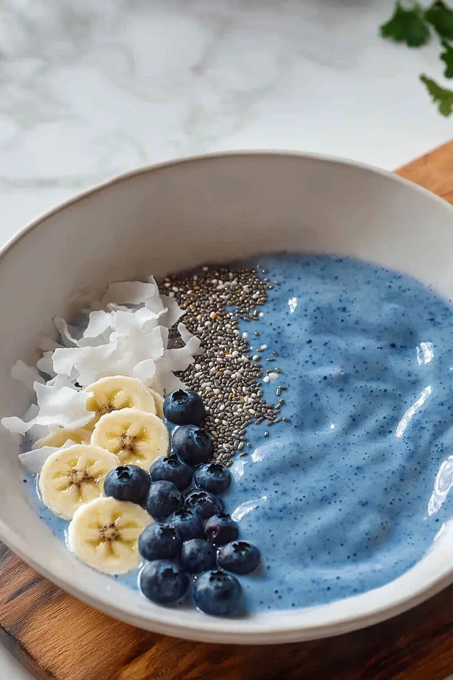 Blaue Smoothie-Schüssel mit frischen Zutaten und buntem Obst